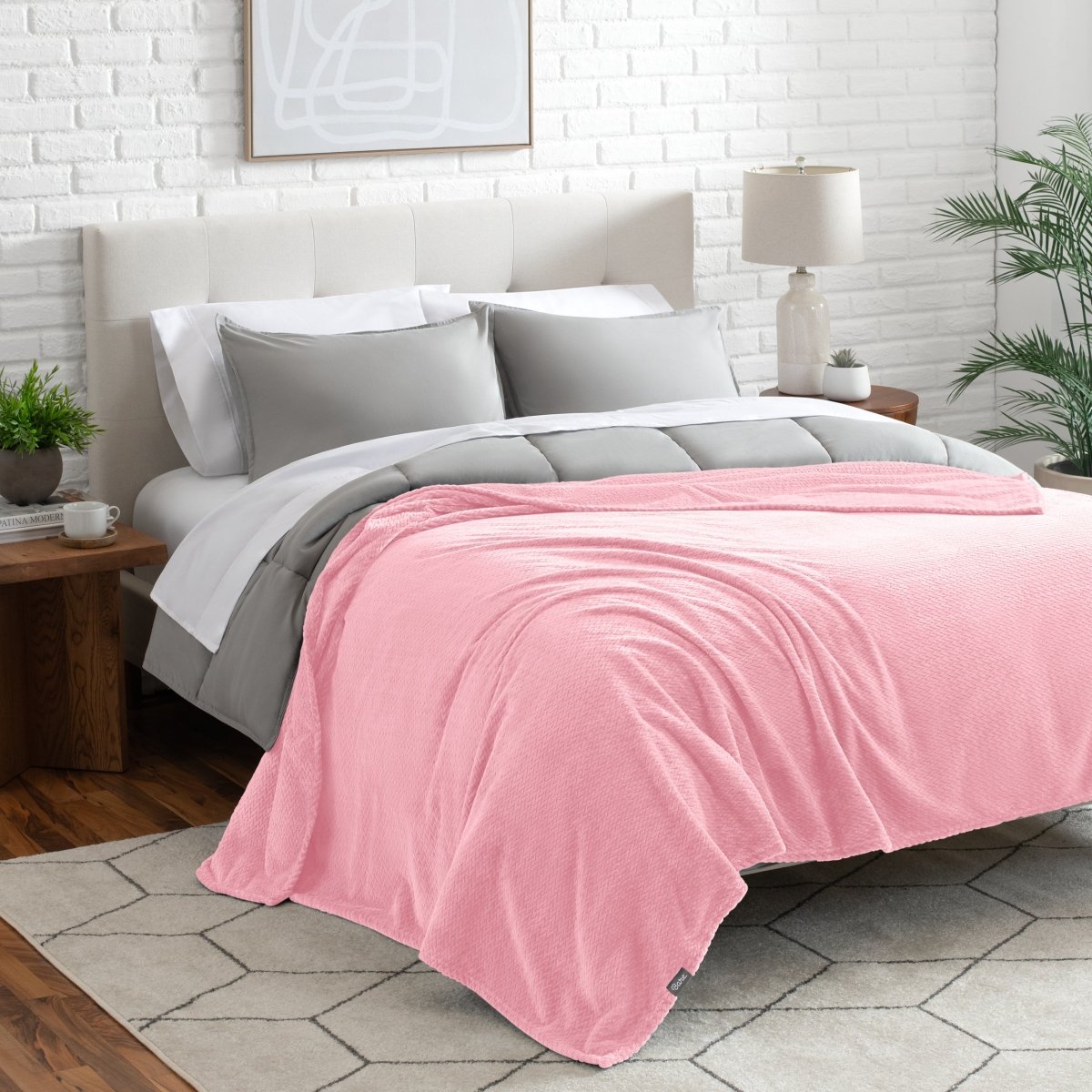 Neatly made bed with a blanket draped over the end of the bed