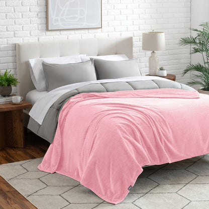 Neatly made bed with a blanket draped over the end of the bed