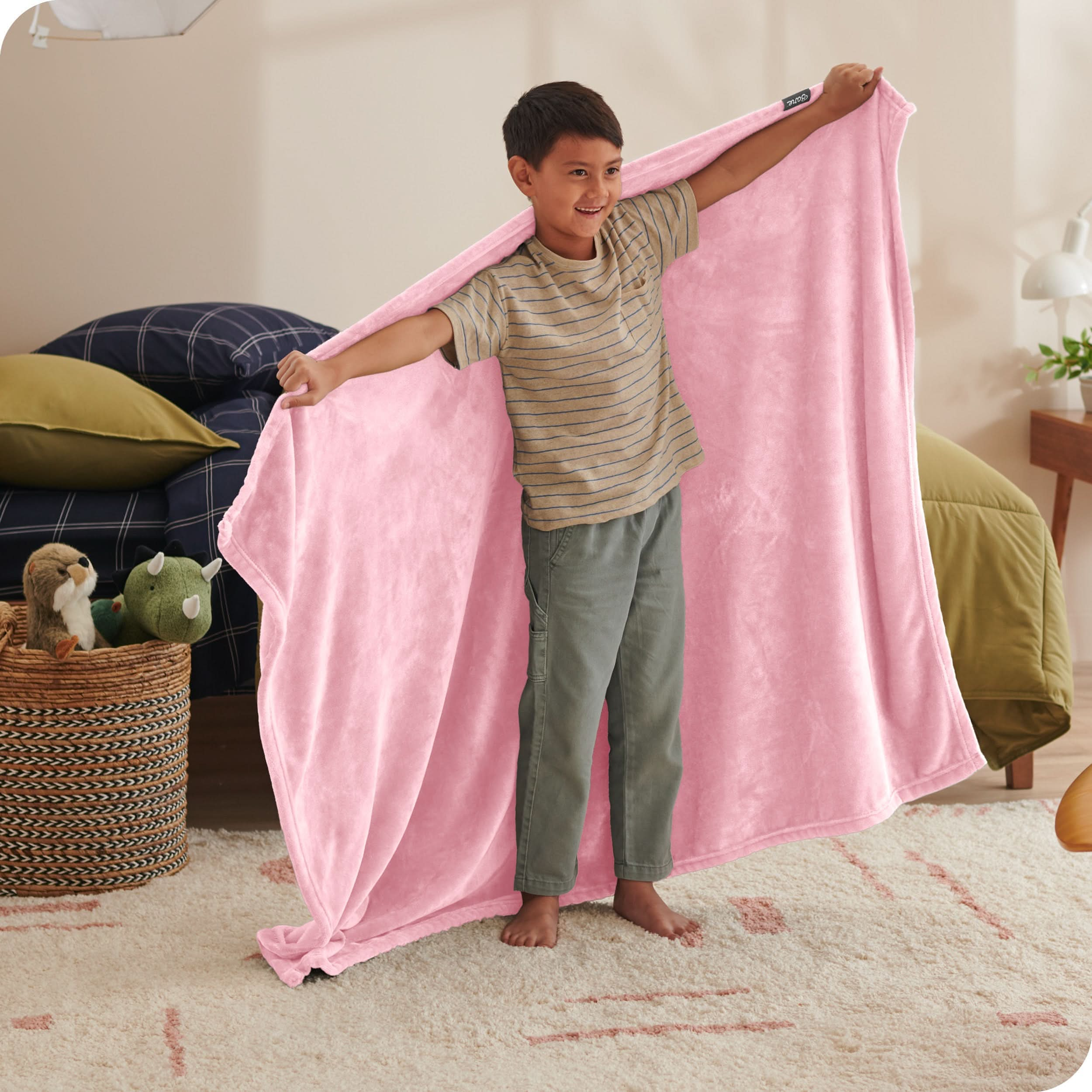 A child has his arms stretched out while holding a microplush blanket behind him