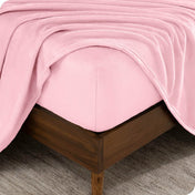 The corner of a bed frame and mattress with a fitted sheet and flat sheet on it.