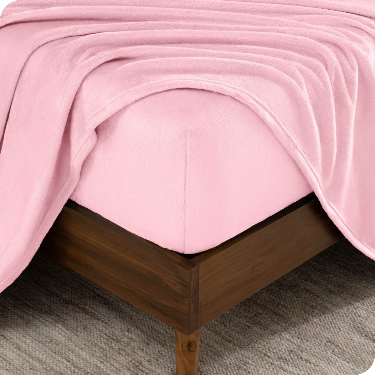 The corner of a bed frame and mattress with a fitted sheet and flat sheet on it.