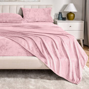 Microplush sheet set on a bed in a bedroom setting with a nightstand and lamp.
