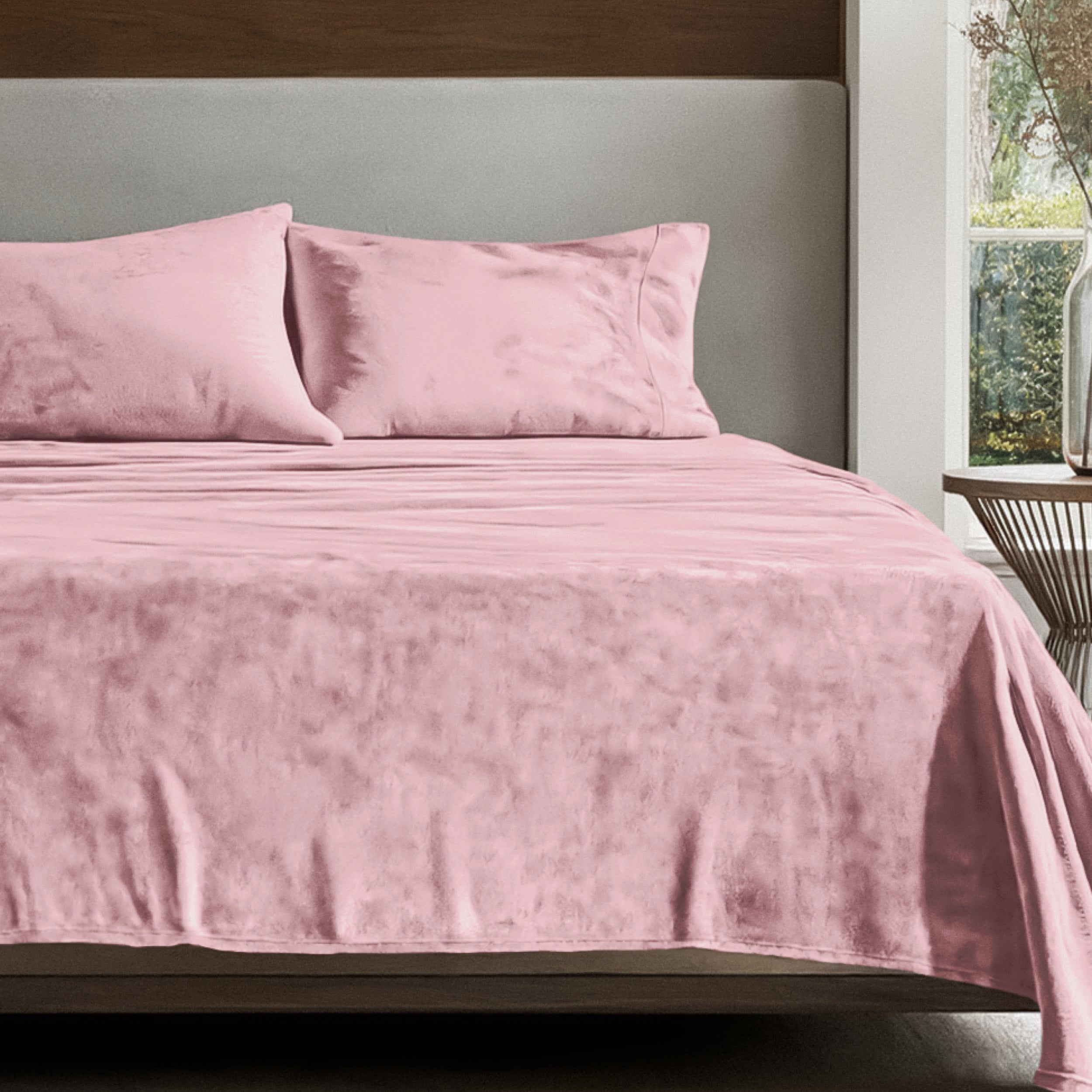 Microplush sheet set on a bed in a bedroom setting with a nightstand and lamp.