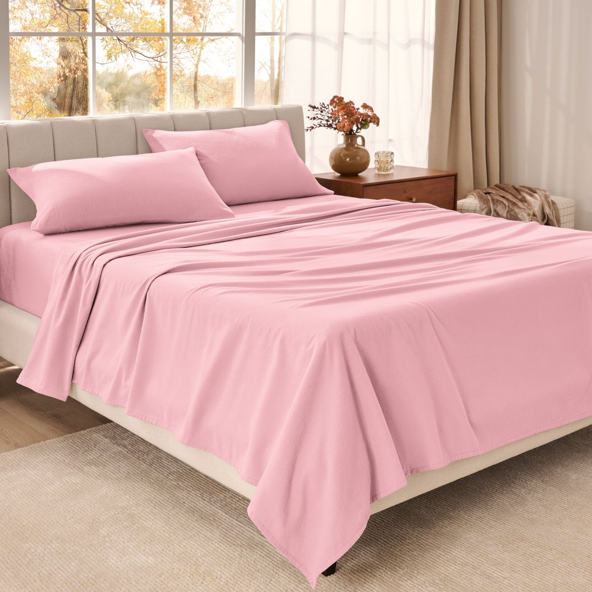 Bed sheets on a neatly made bed in a bright bedroom with large windows.