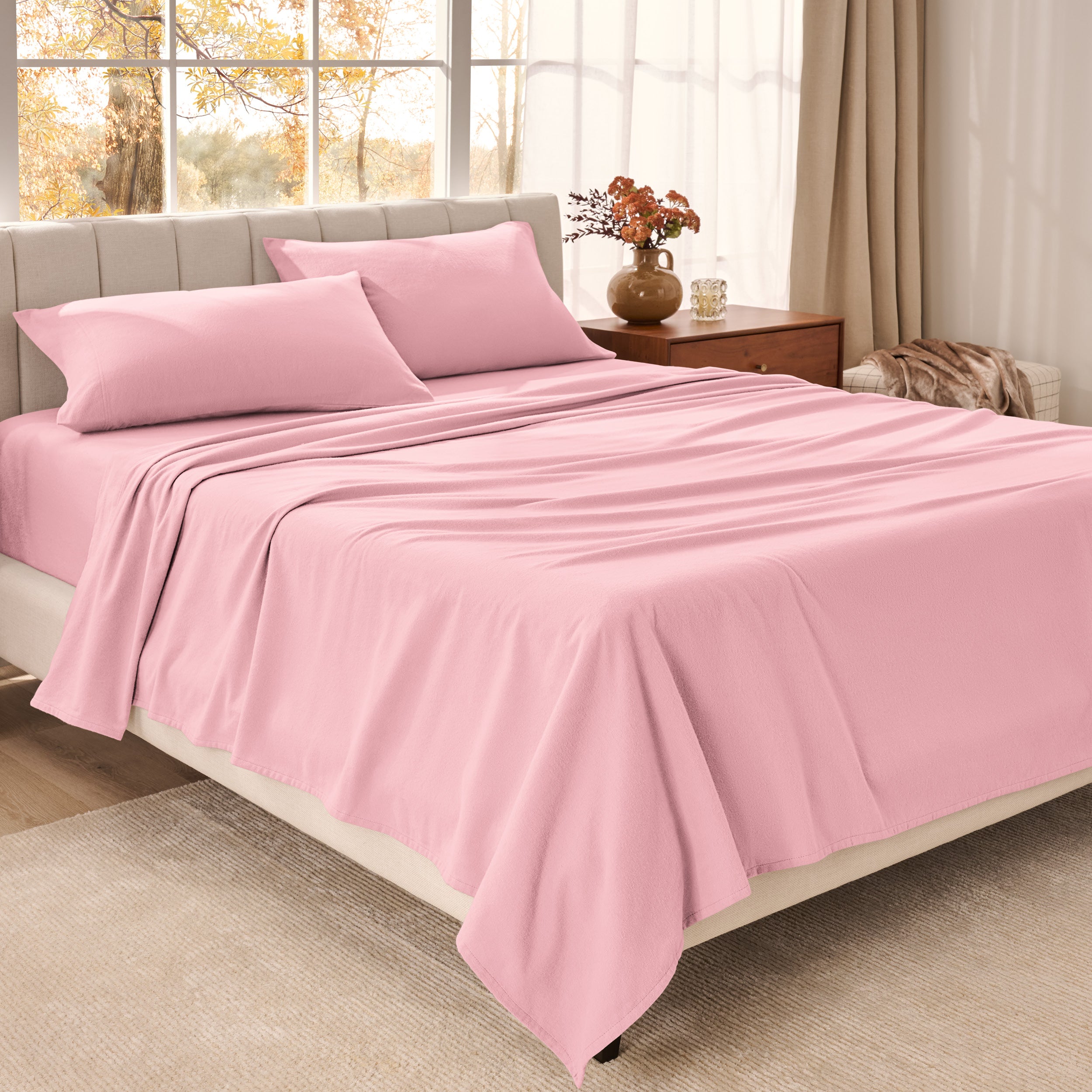 Bed sheets on a neatly made bed in a bright bedroom with large windows.