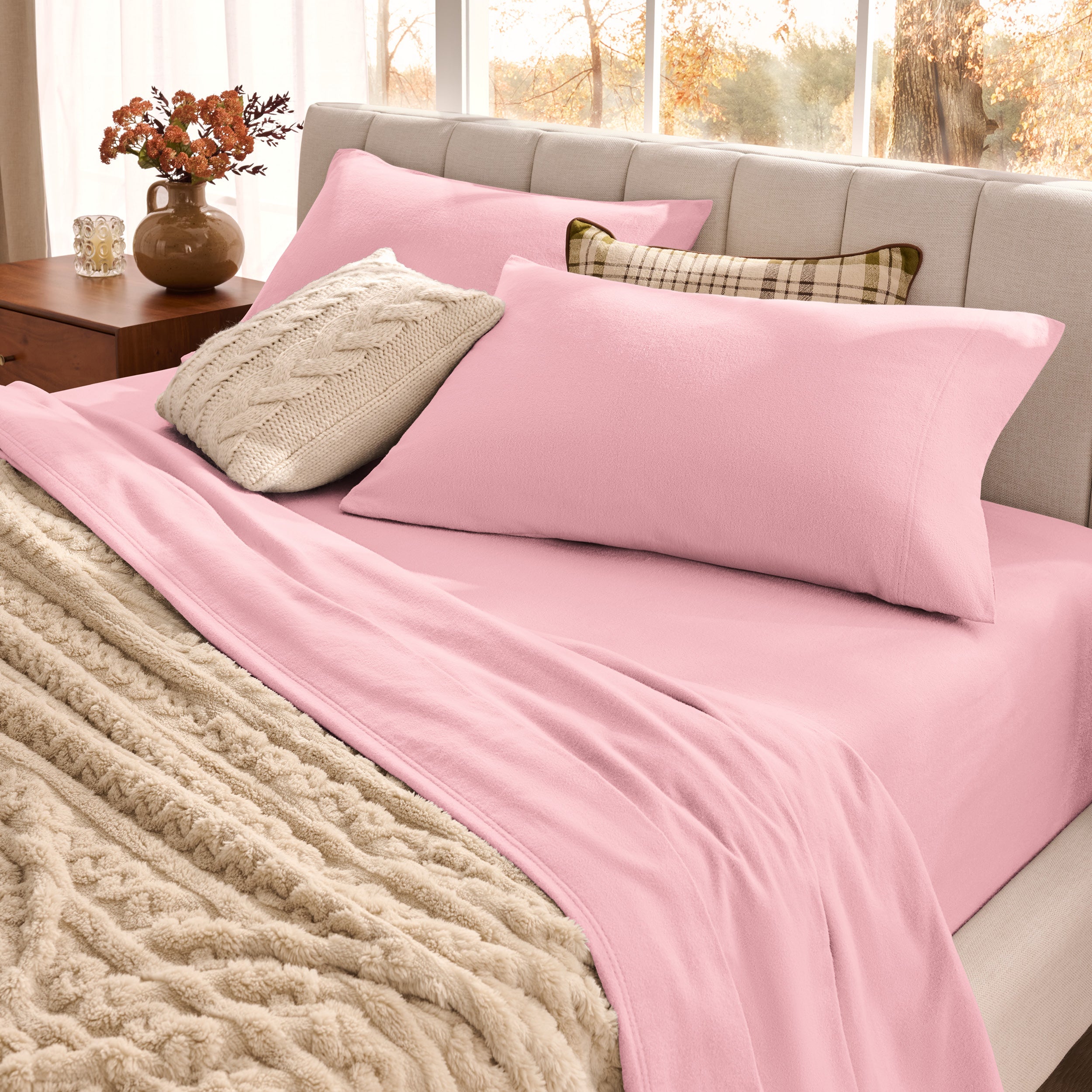 Neatly made bed with organic flannel sheets  and a beige blanket in a bright bedroom.