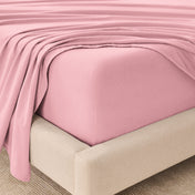 Fitted sheet and top sheet on a mattress with a beige bed frame