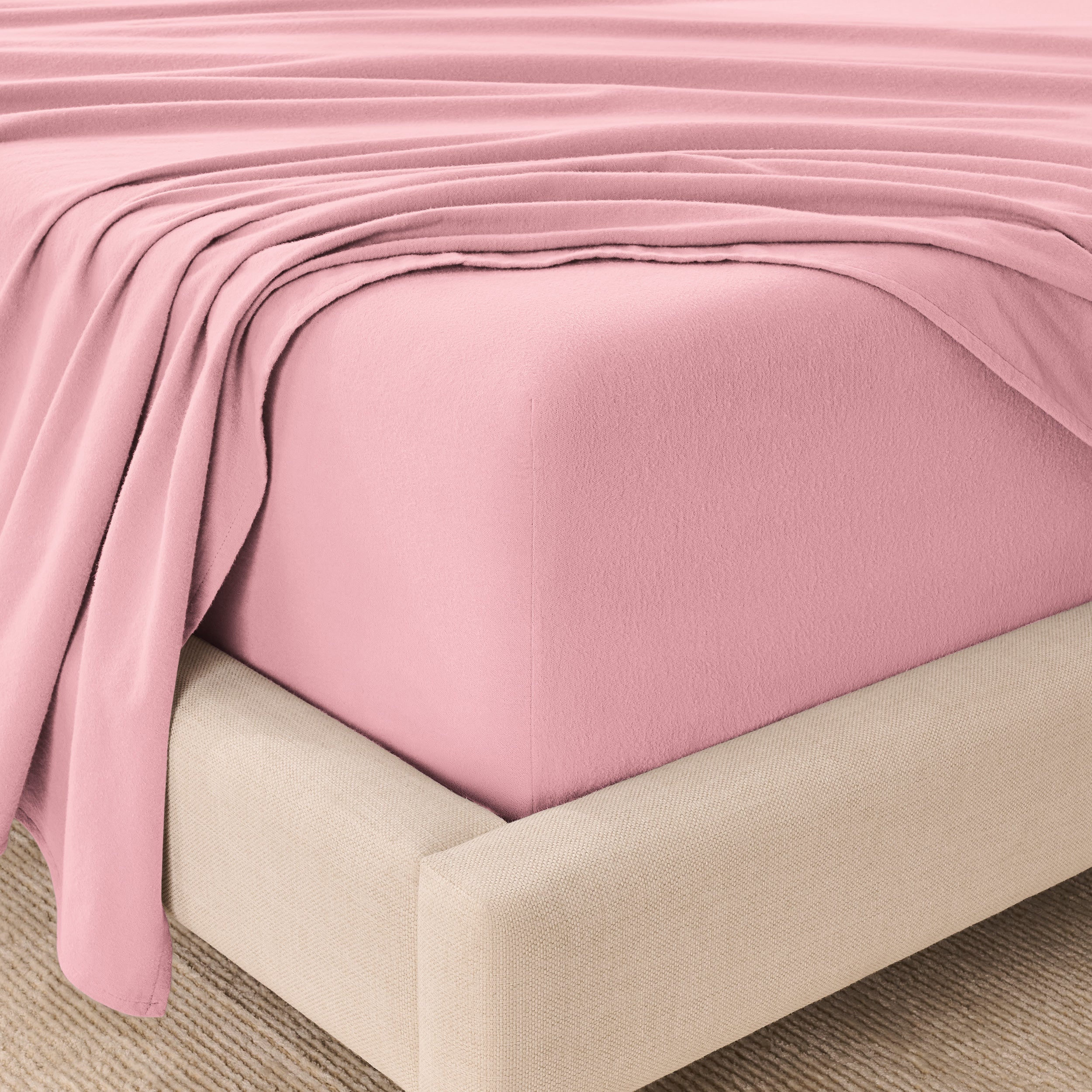 Fitted sheet and top sheet on a mattress with a beige bed frame