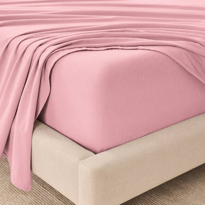 Fitted sheet and top sheet on a mattress with a beige bed frame