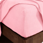 Corner of the bed with a fitted sheet on the mattress and a flat sheet draped over the side and end