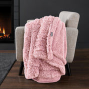 Sherpa blanket draped over an armchair in front of a fireplace.