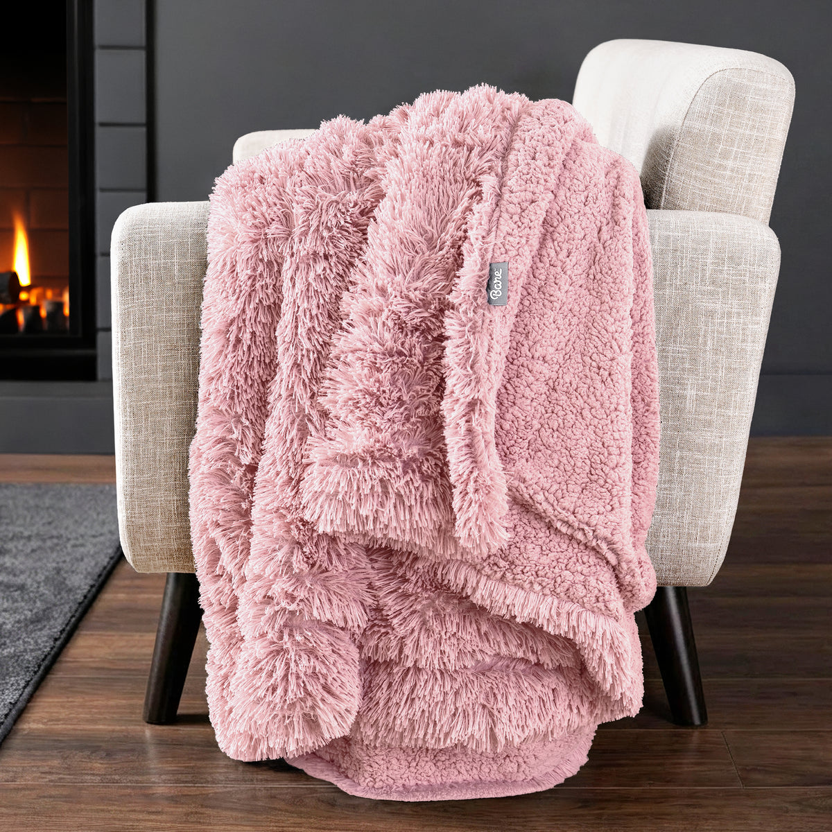 Sherpa blanket draped over an armchair in front of a fireplace.
