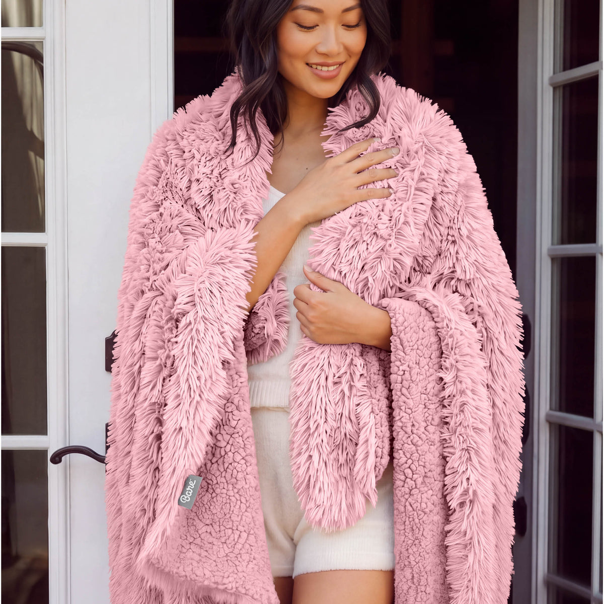 A woman standing with a shaggy blanket wrapped around her