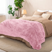 A shaggy faux fur blanket on the end of a bed