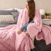 Fluffy blanket draped over a woman sitting on the end of a bed