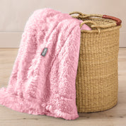 A blanket hanging over the edge of a wicker basket