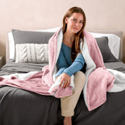 A woman sitting on a bed with a Sherpa blanket around her