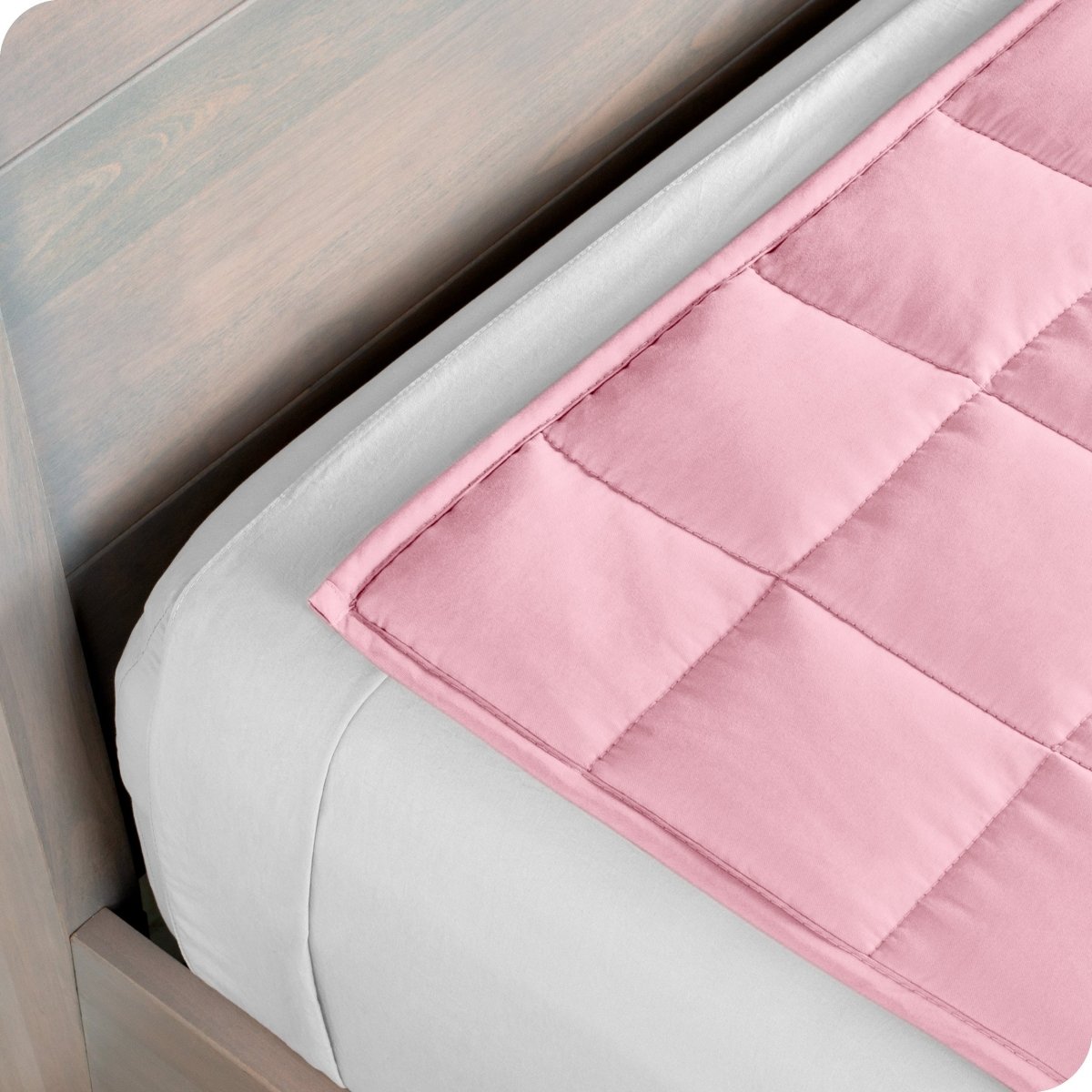 Close up of a weighted blanket on top of a bed made with white sheets