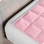 Close up of a weighted blanket on top of a bed made with white sheets