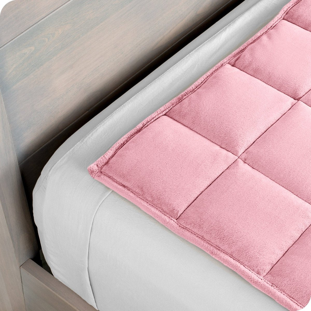 Close up of a weighted blanket on top of a bed made with white sheets