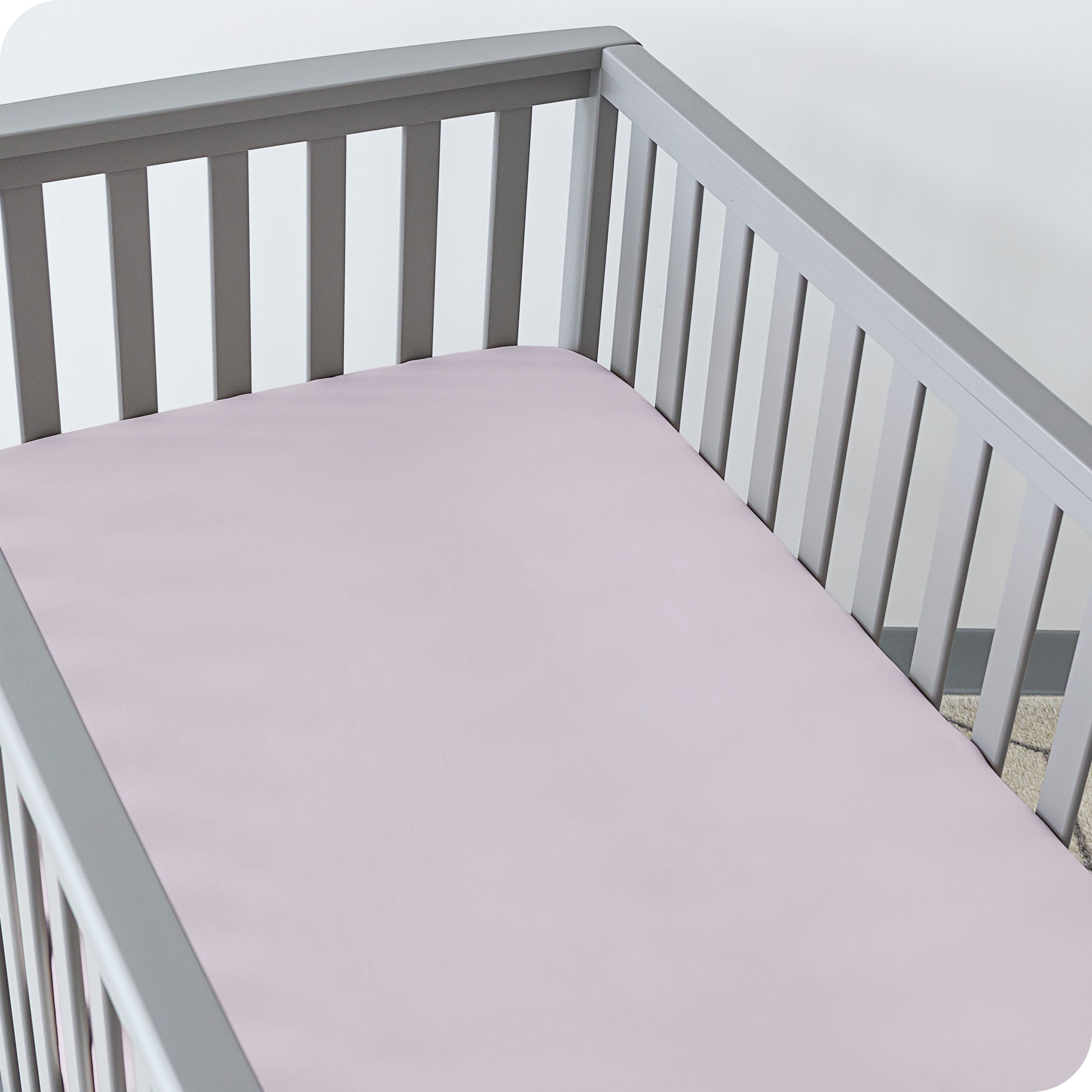 A crib with a fitted sheet on the mattress