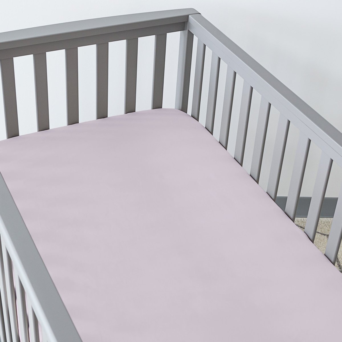 Gray crib with a fitted sheet on the mattress