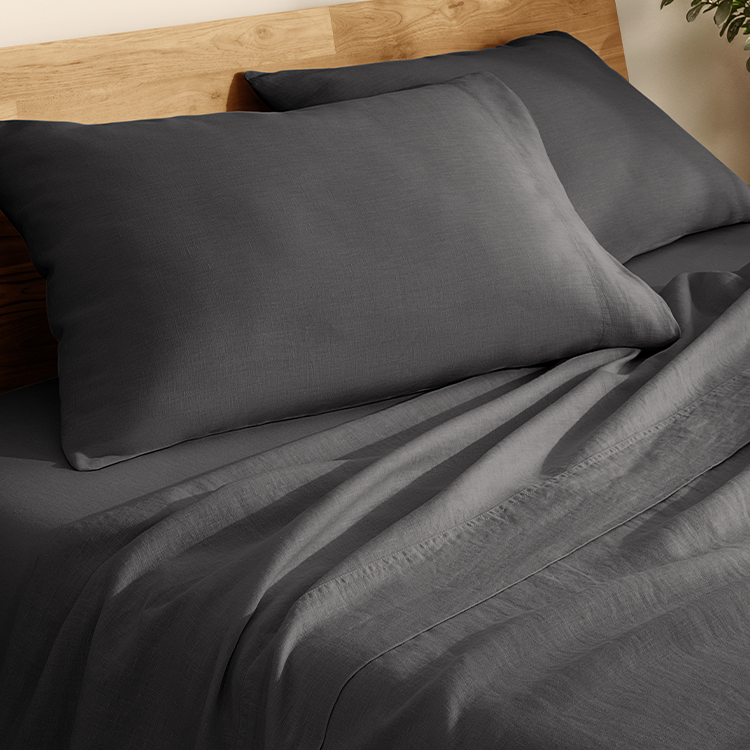 Gray bedding set on a bed with wooden headboard