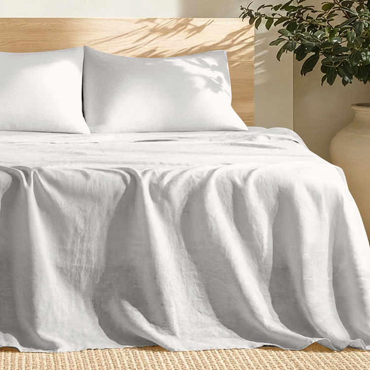 Gray bedding set on a bed with a wooden headboard and plant in the background