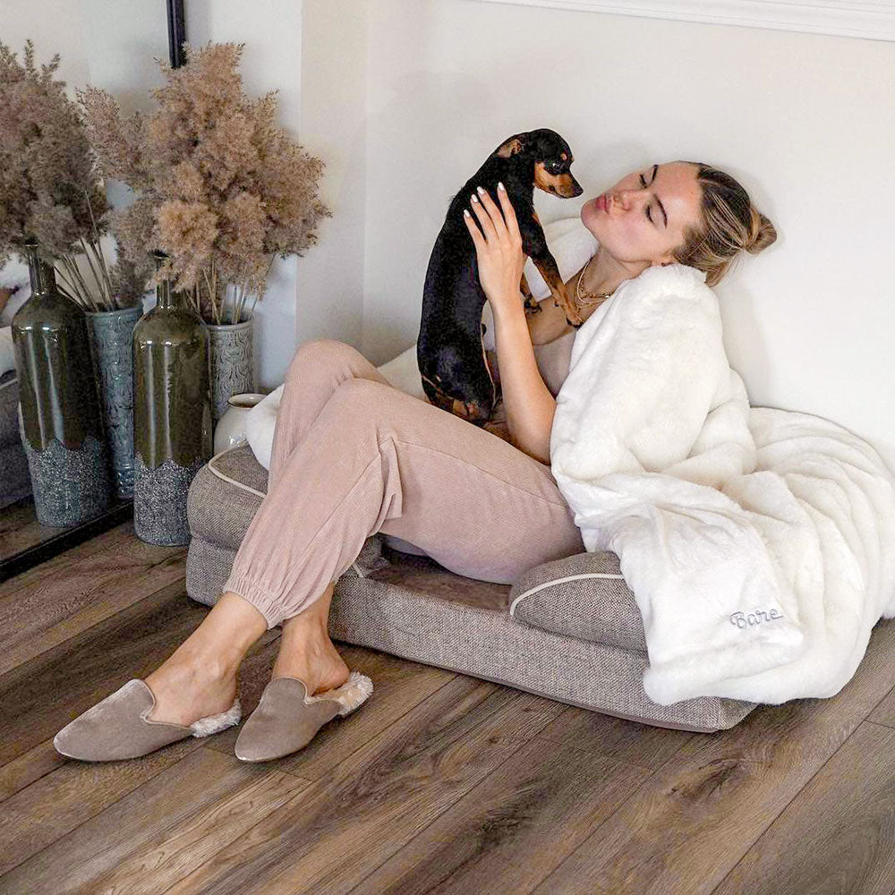 Lady with a sherpa blanket in a dog bed holding a puppy