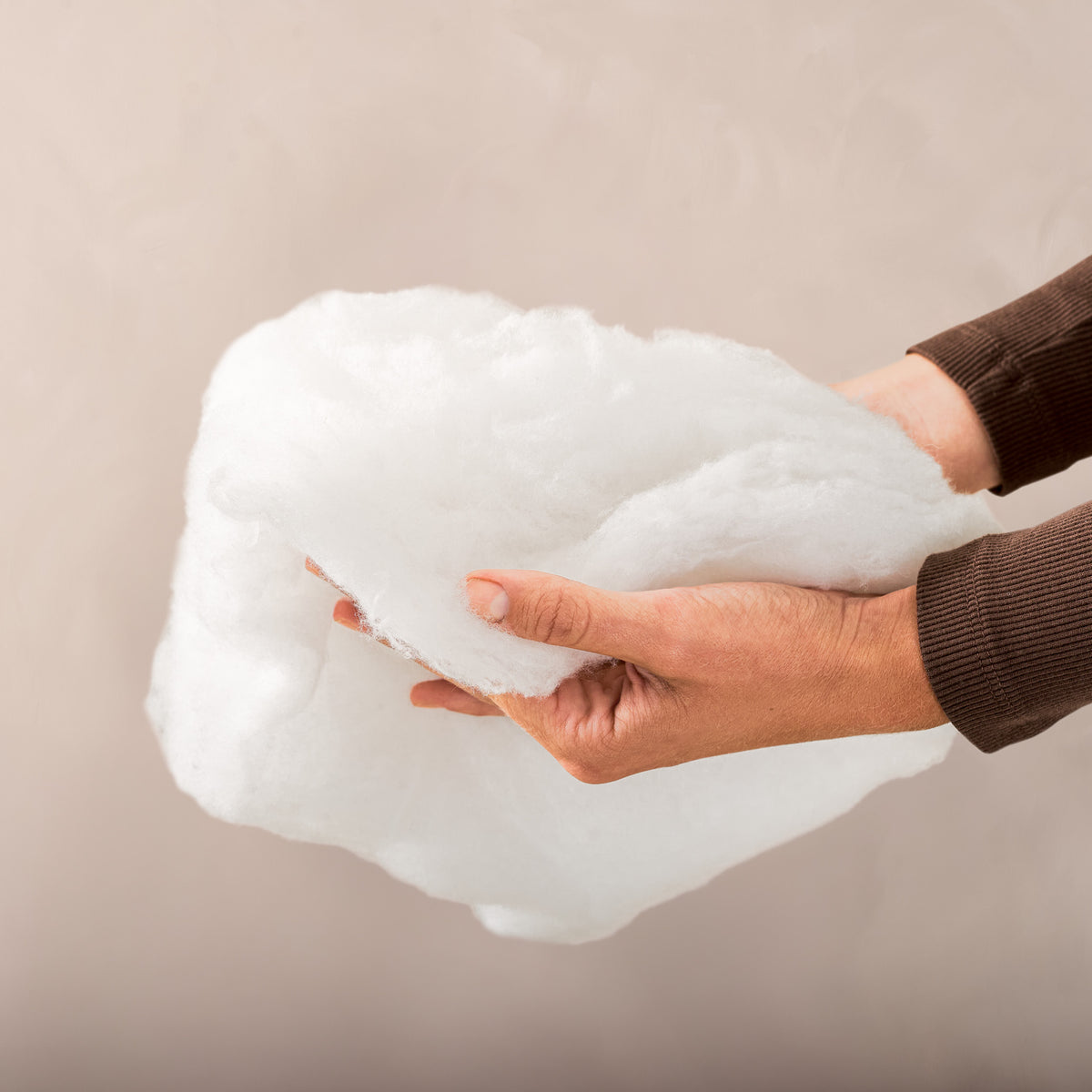 A woman holding the hollow fiber fill of a pillow
