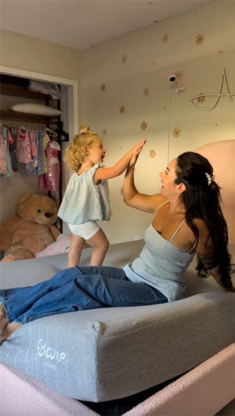 Mom and young daughter holding hand on a new mattress 