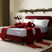 Decorative bed with red ribbon and 'Bare' mattress in a festive bedroom setting.