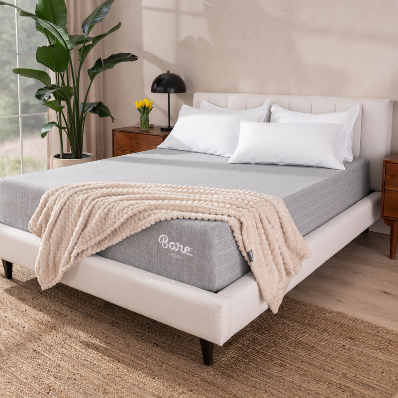 A mattress with a blanket draped over the bottom corner