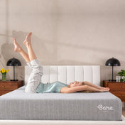 A woman is lying on a mattress set on a bed frame