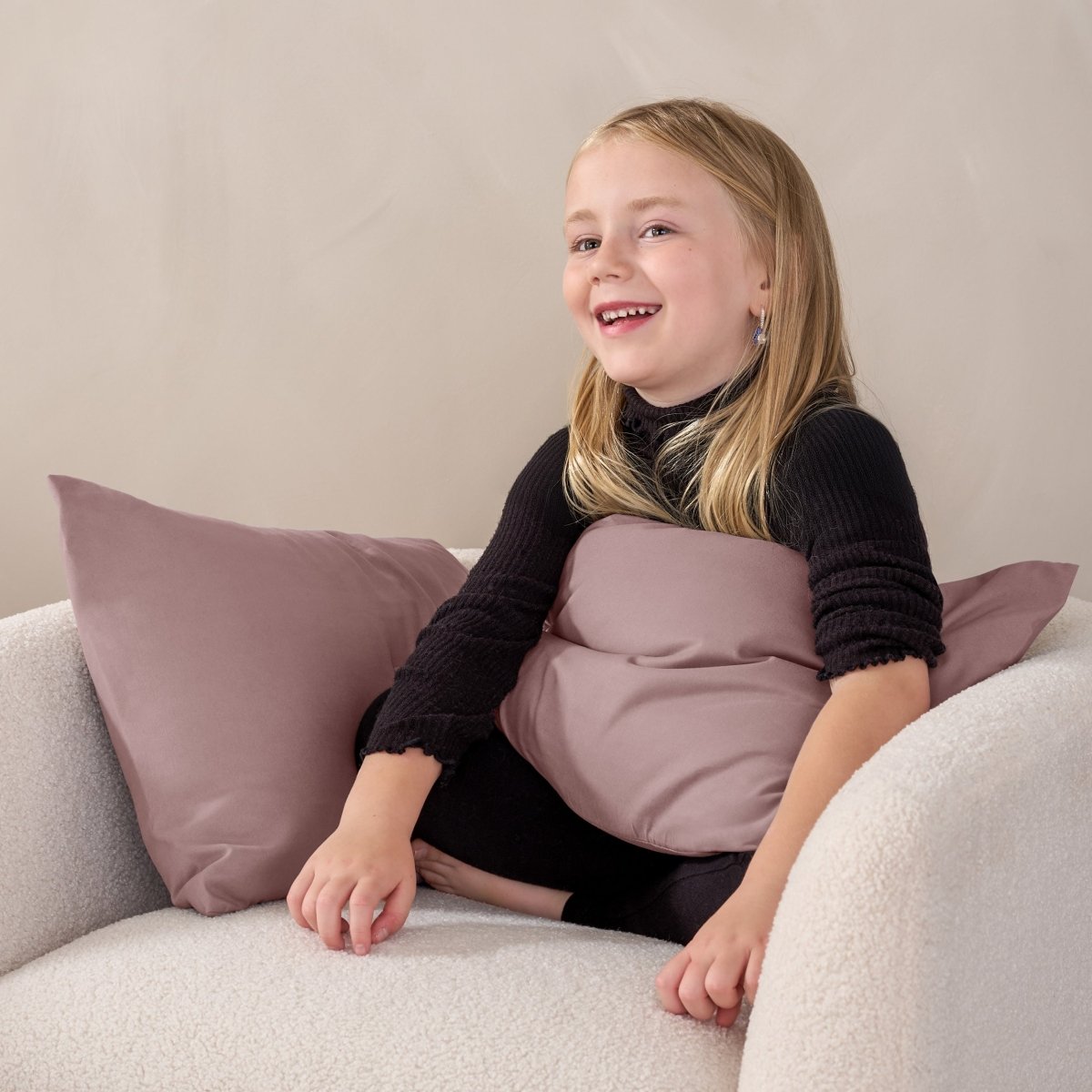 A child sitting while holding a microfiber pillowcase covered pillow