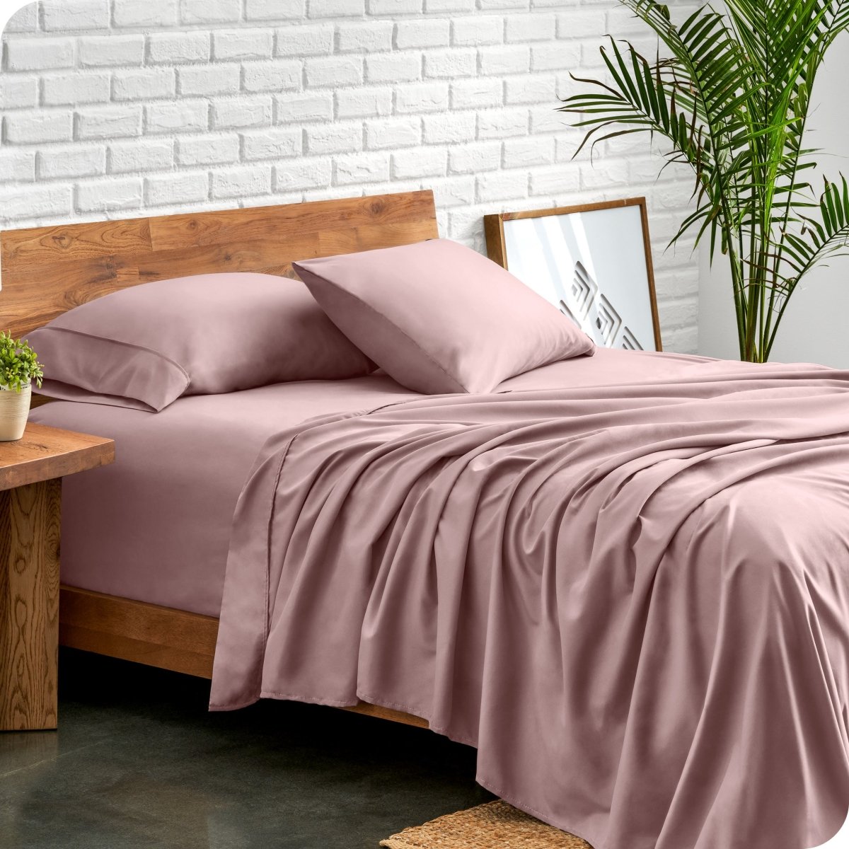 Bed with microfiber sheets against a white brick wall