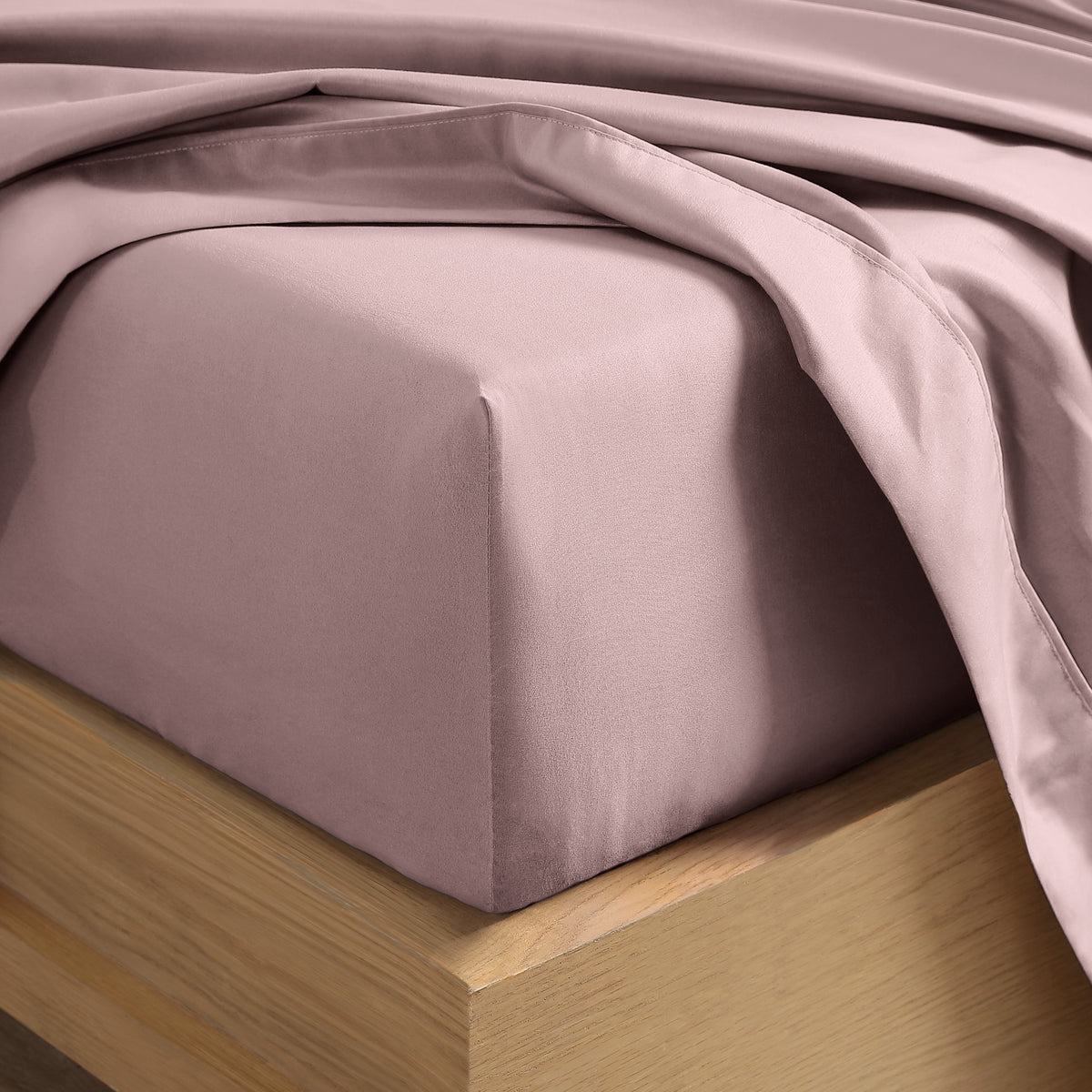 Close up of the corner of a mattress with a fitted sheet and flat sheet on it