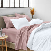 A side view of a bed made with microfiber sheets and a white duvet cover