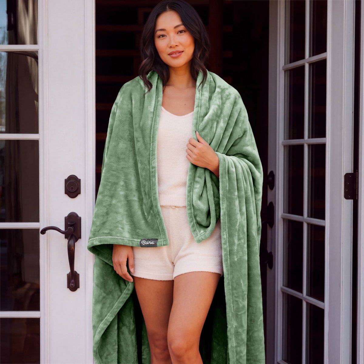A woman standing with a microplush blanket wrapped around her