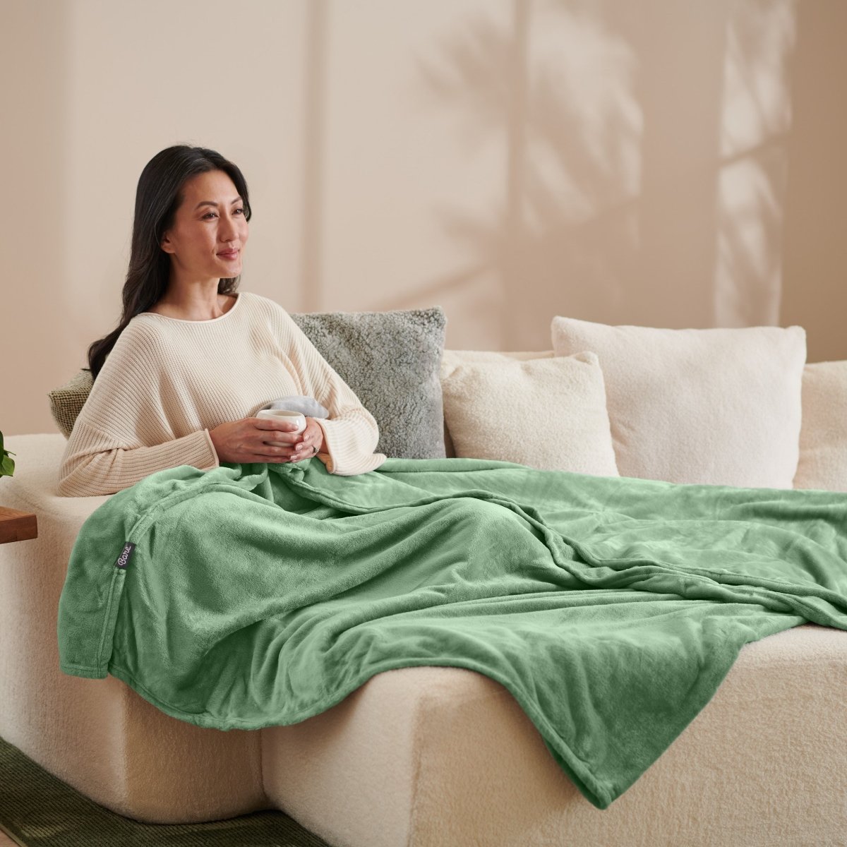A woman sitting on a couch with a microplush blanket on her lap