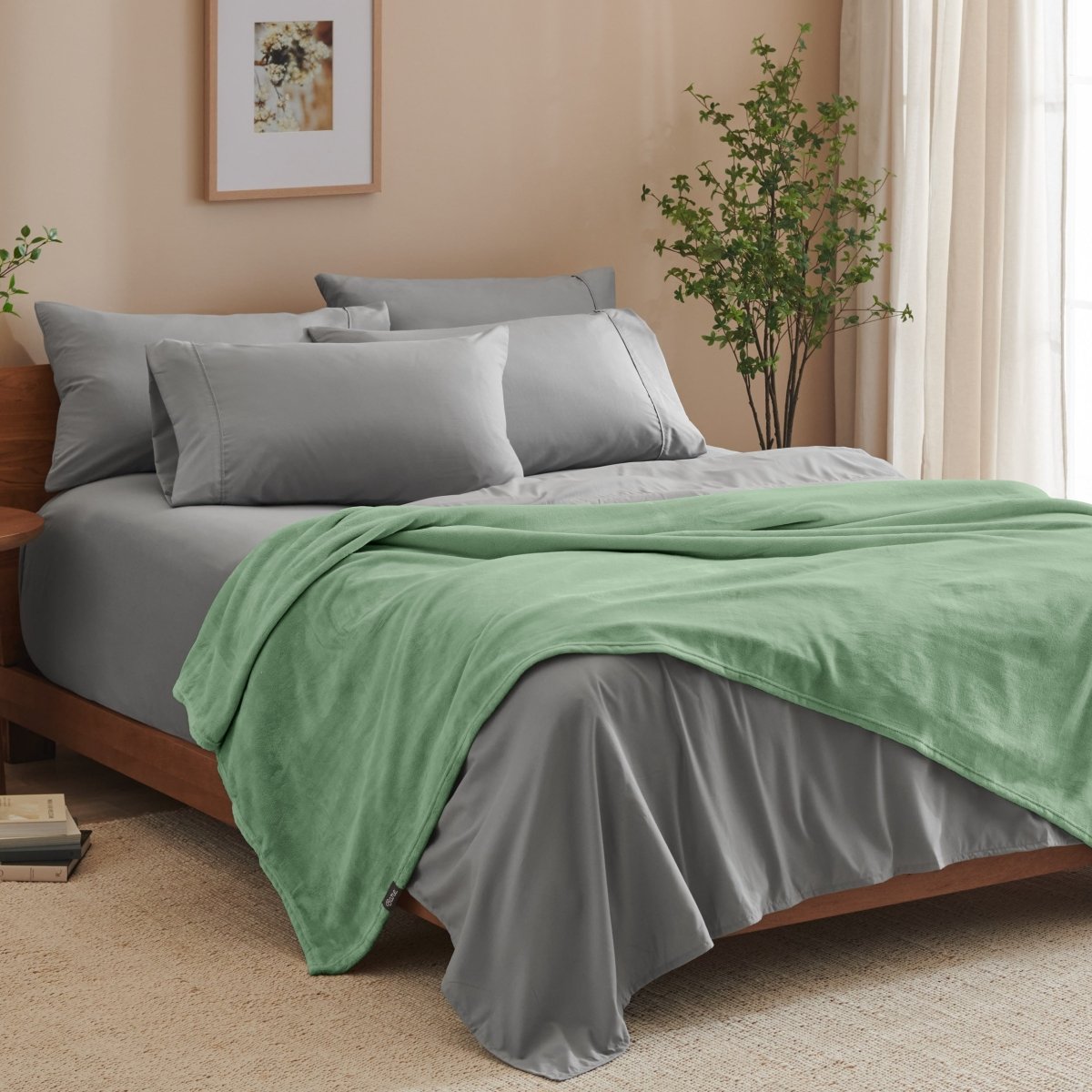 A bed made with grey sheets and a microplush blanket