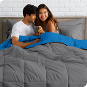A couple sitting in a bed made with a reversible comforter and sheet set