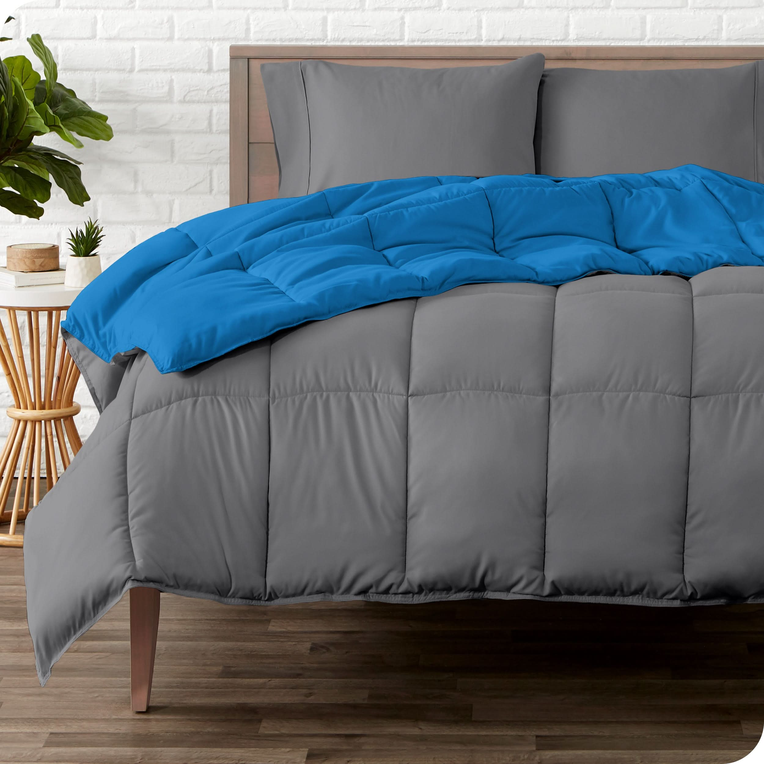 A wooden bed frame with a reversible comforter and sheet set on the mattress