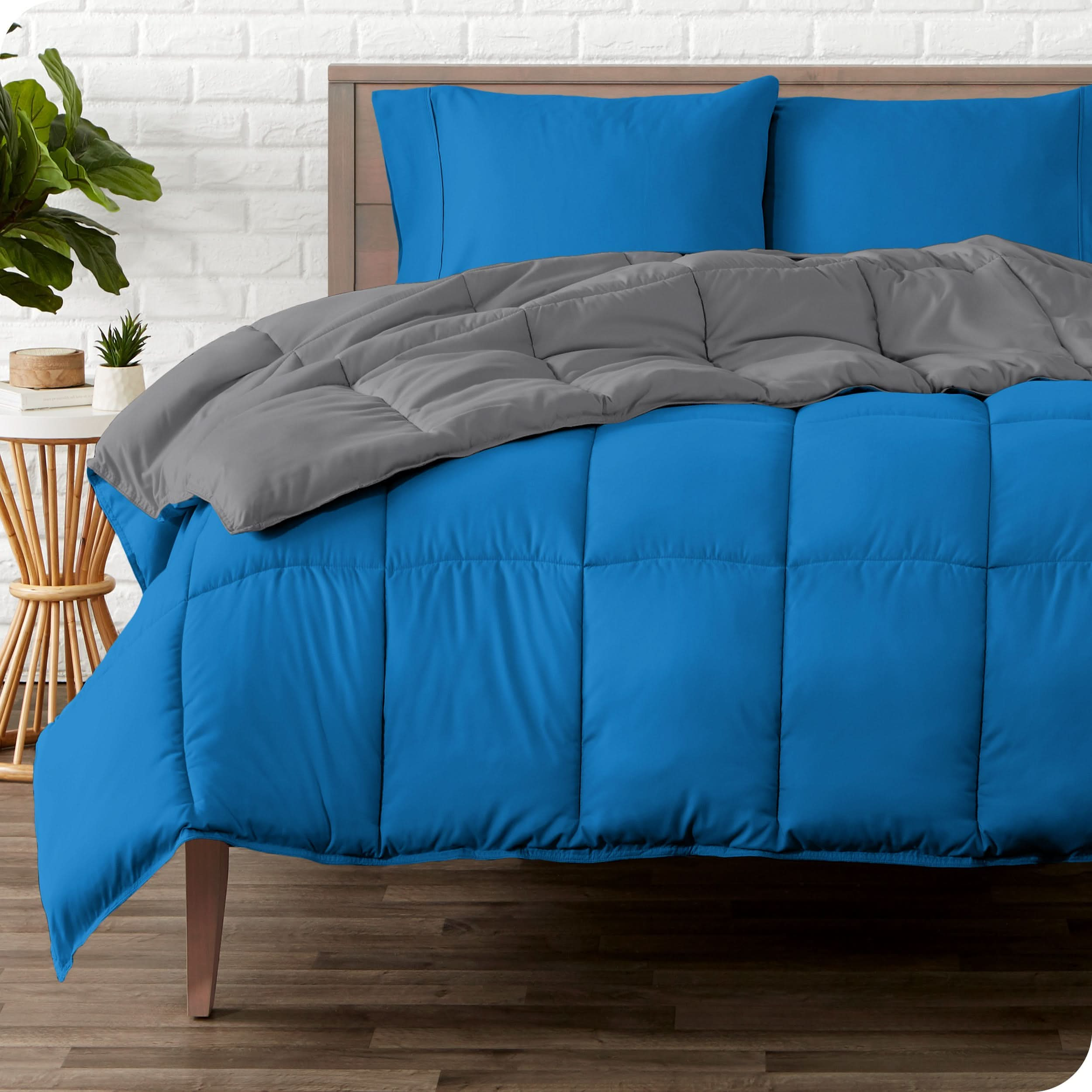 A wooden bed frame with a reversible comforter and sheet set on the mattress