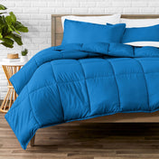 Comforter set on a bed with a white brick wall and plant in the background