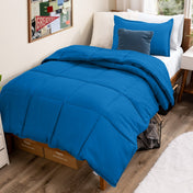Bed with comforter and pillows in a dorm room
