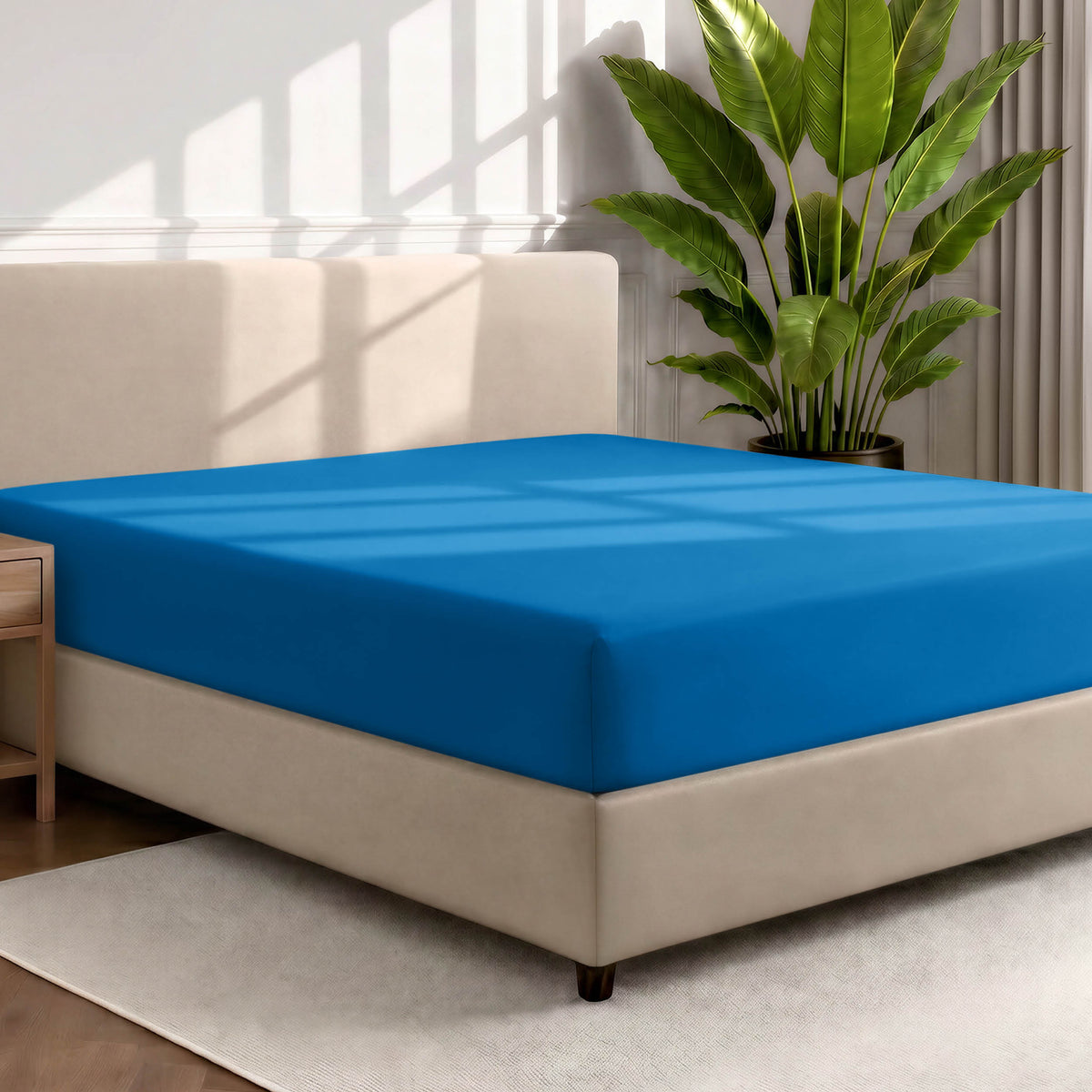 Bed with a fitted sheet in a room with a large plant and rug