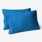 Two pillows on a white background with blue pillowcases on them