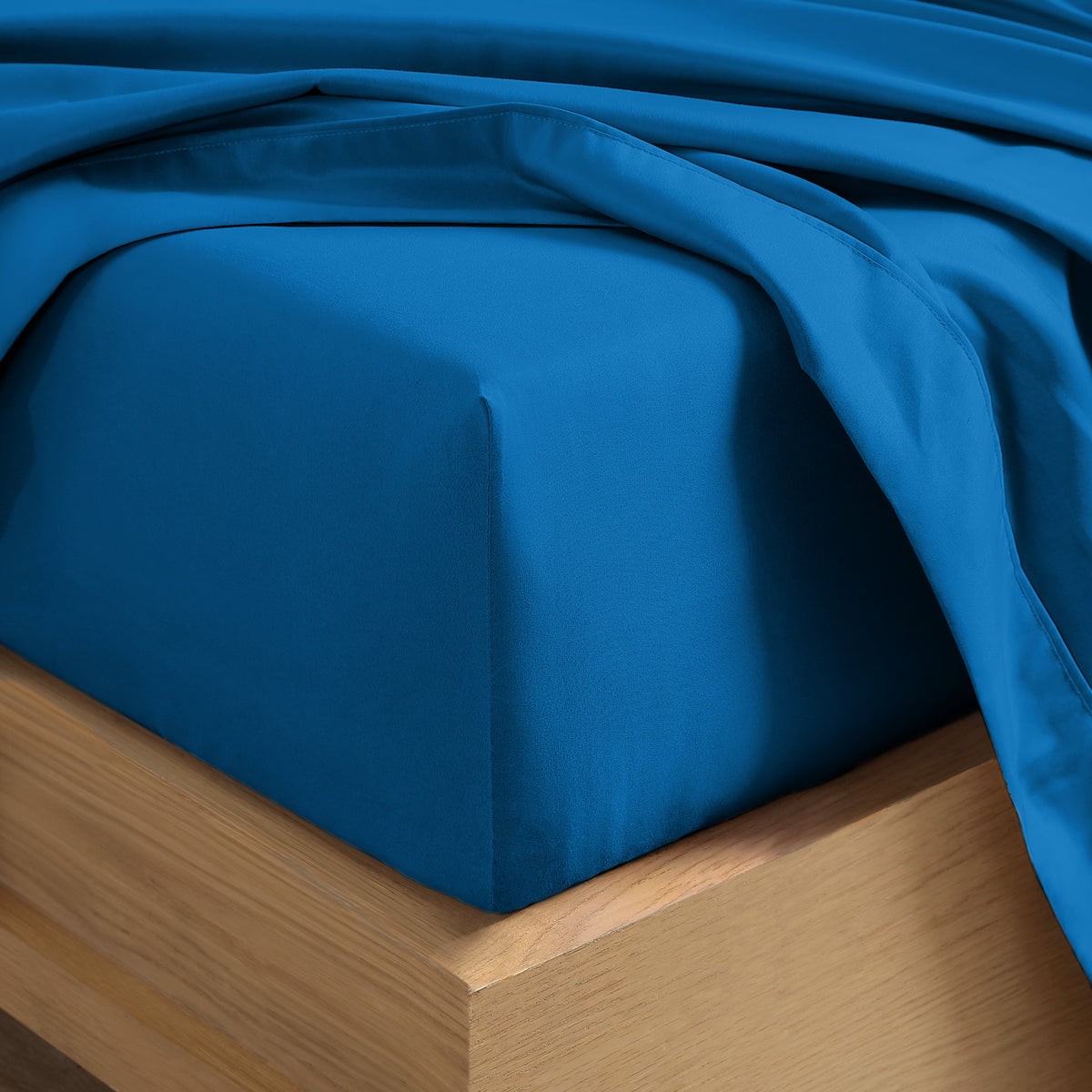 Close up of the corner of a mattress with a fitted sheet and flat sheet on it
