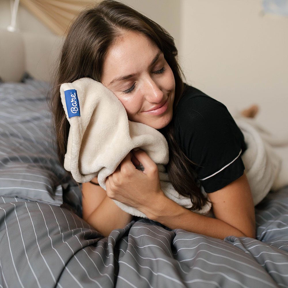 Woman holding a microfiber blanket to her face feeling the softness